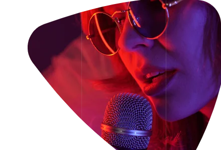Cantora de óculos redondos ao microfone, sob luz vermelha