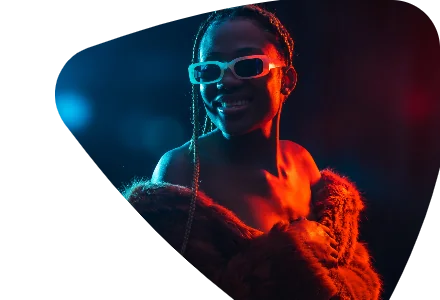Creator de tranças e óculos claros, sorrindo sob luz azul e vermelha